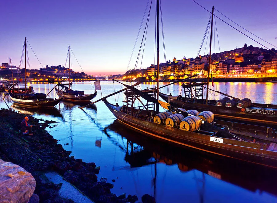Traditional "rabelo" boats, which were once used to deliver port wine from the Douro Valley, line Porto's harbor at sunset